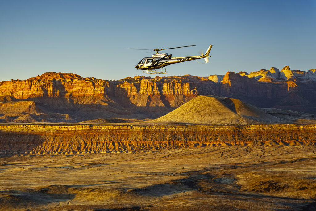 A helicopter flying over Utah’s stunning mountain landscape at sunset, captured by Rex Jones, showcasing commercial photography in Utah.